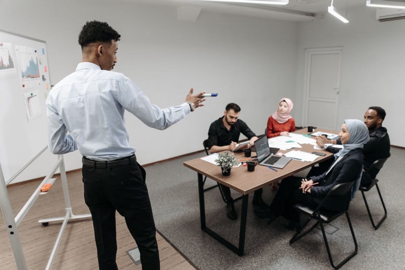 A strategist presenting at a whiteboard to a team around a table — illustrative stock photo