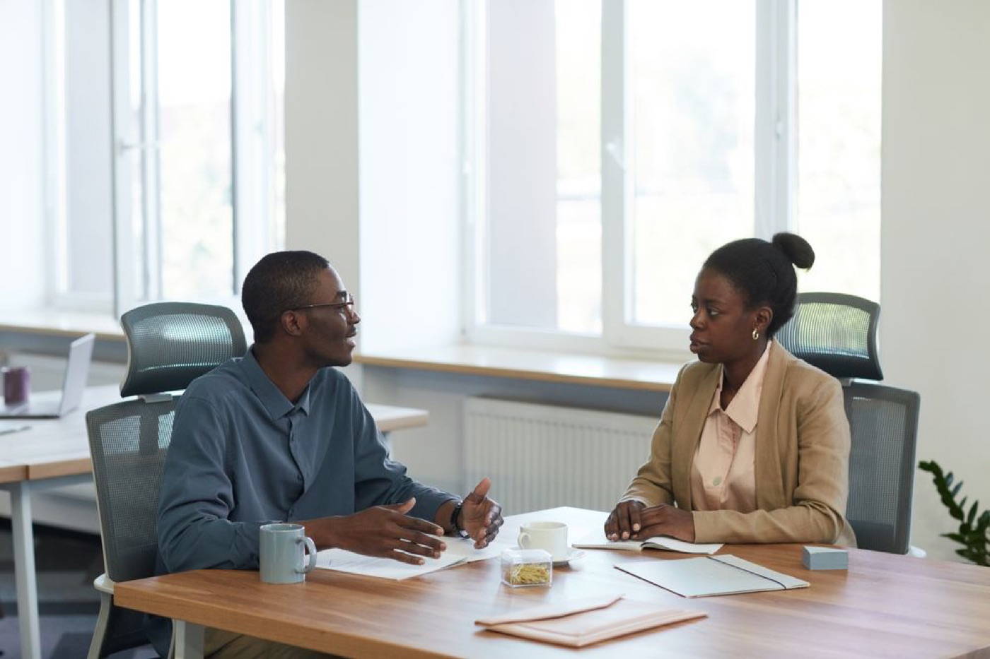 Two professionals in conversation across a desk — illustrative stock photo