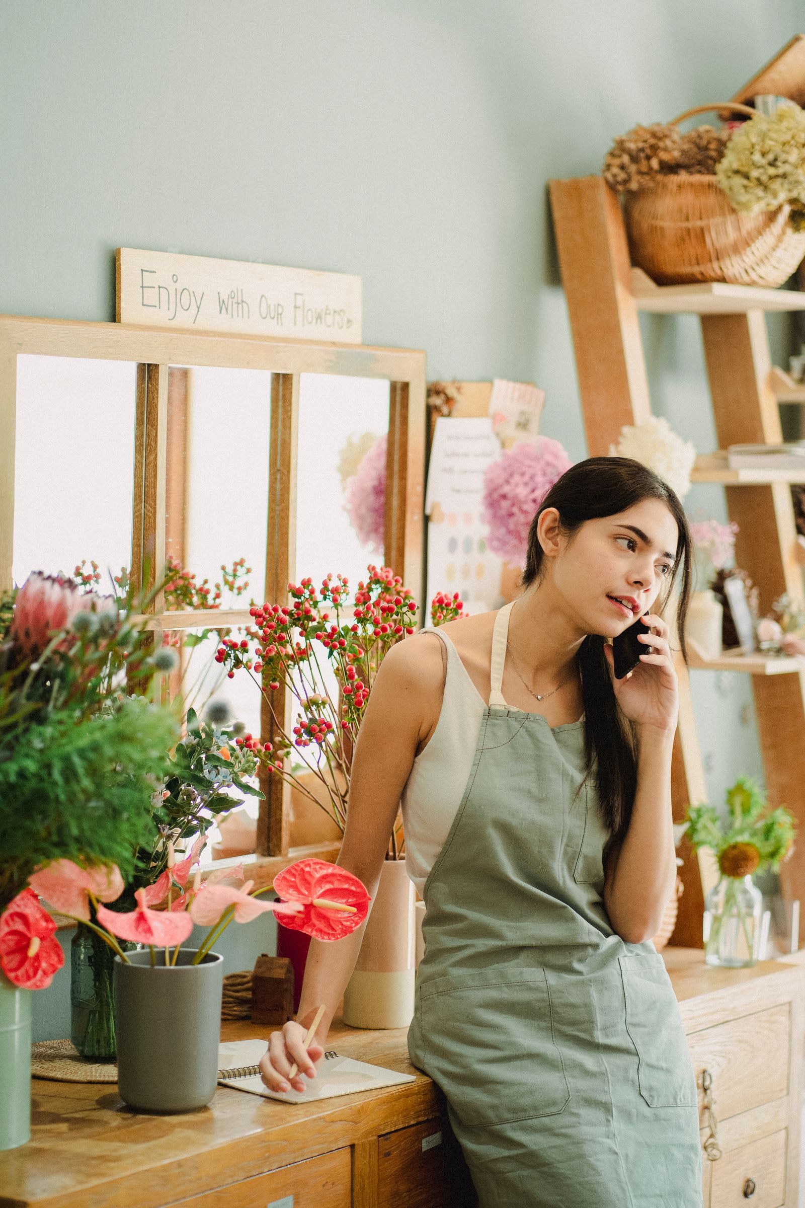 A shop owner taking a phone call behind her counter — illustrative stock photo