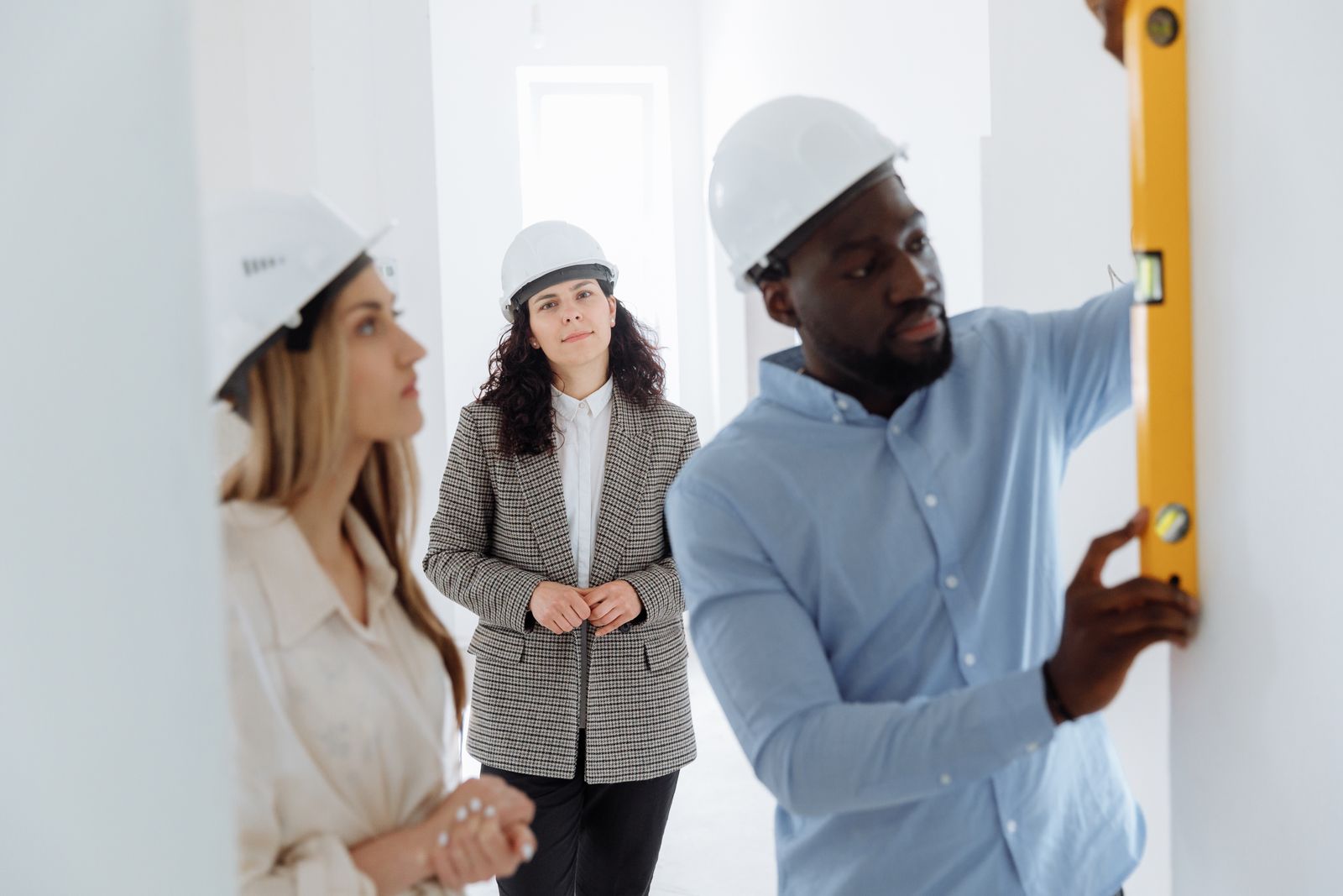 A contractor with a level walking clients through a renovation — illustrative stock photo