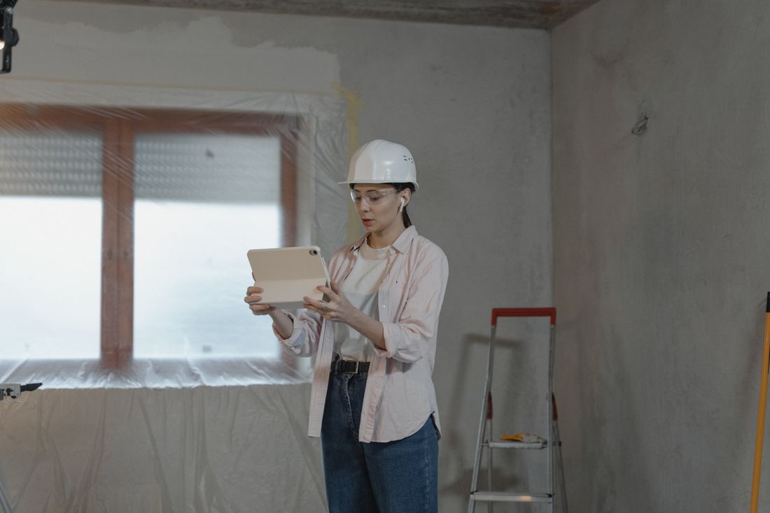 Contractor planning a renovation job on a tablet inside an unfinished room. Illustrative stock photo.
