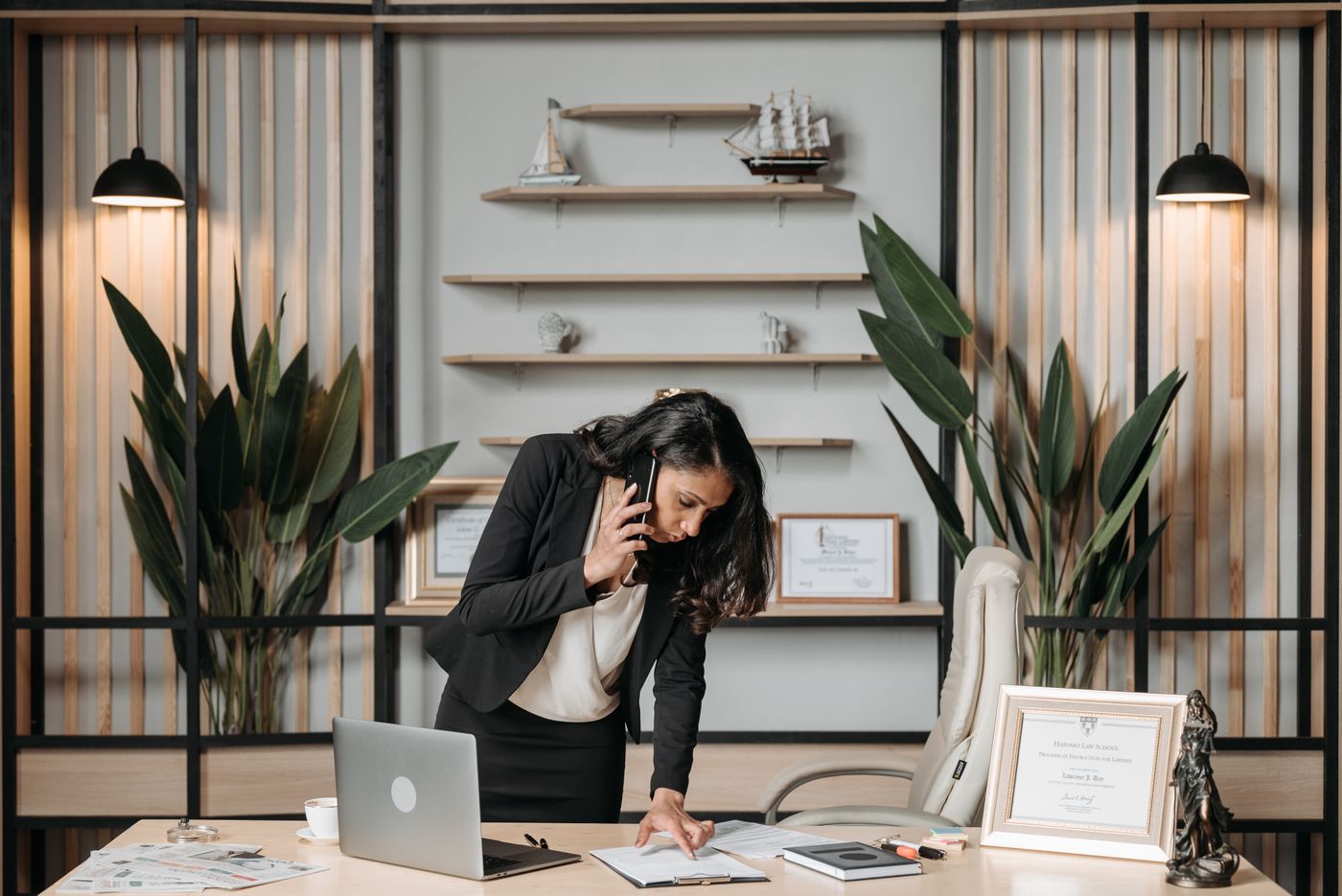 A licensed insurance agent takes a prospect call while reviewing paperwork at her desk