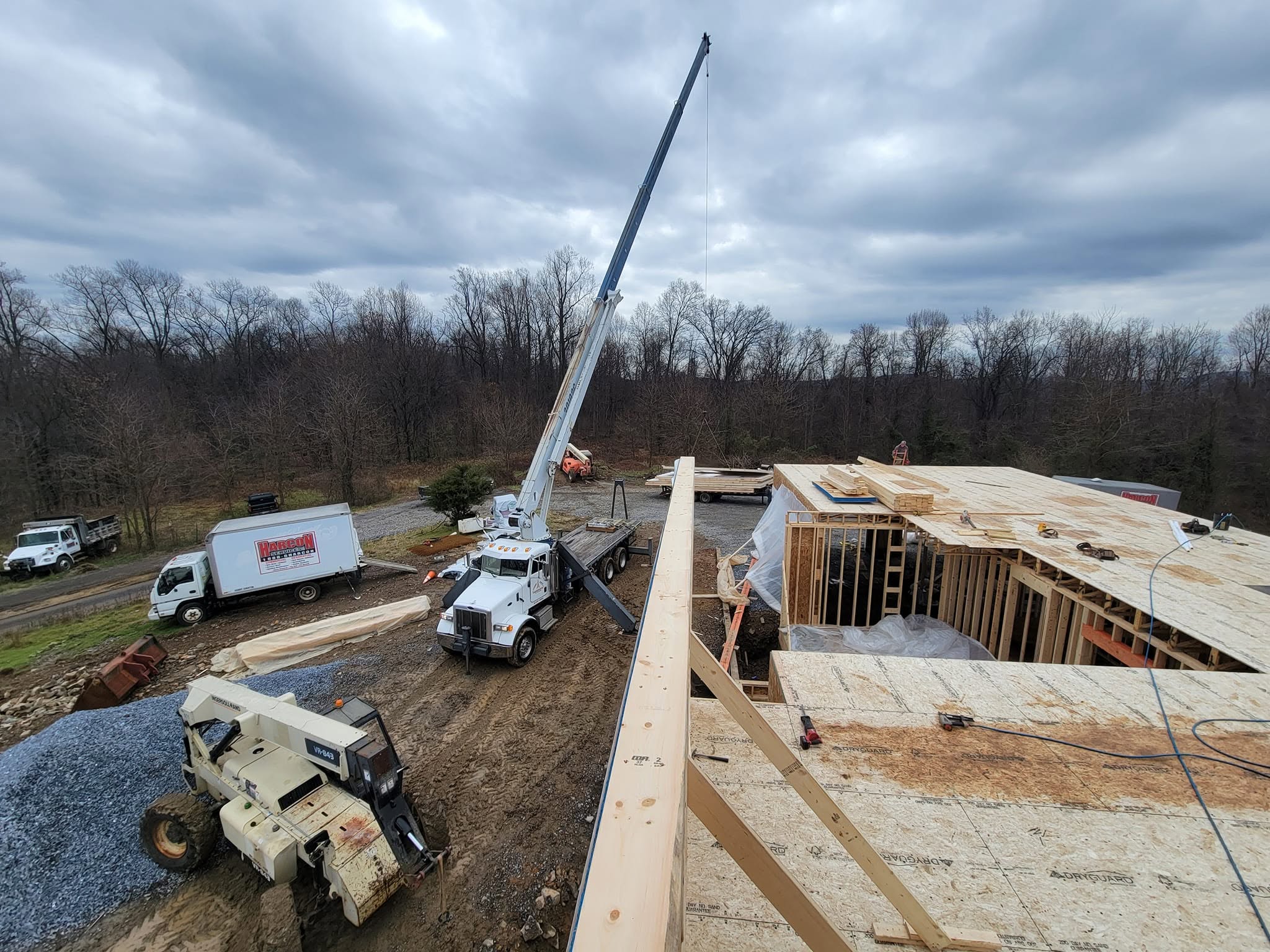 Harcon Services crew setting foundation walls with a crane truck and concrete truck on a wooded lot