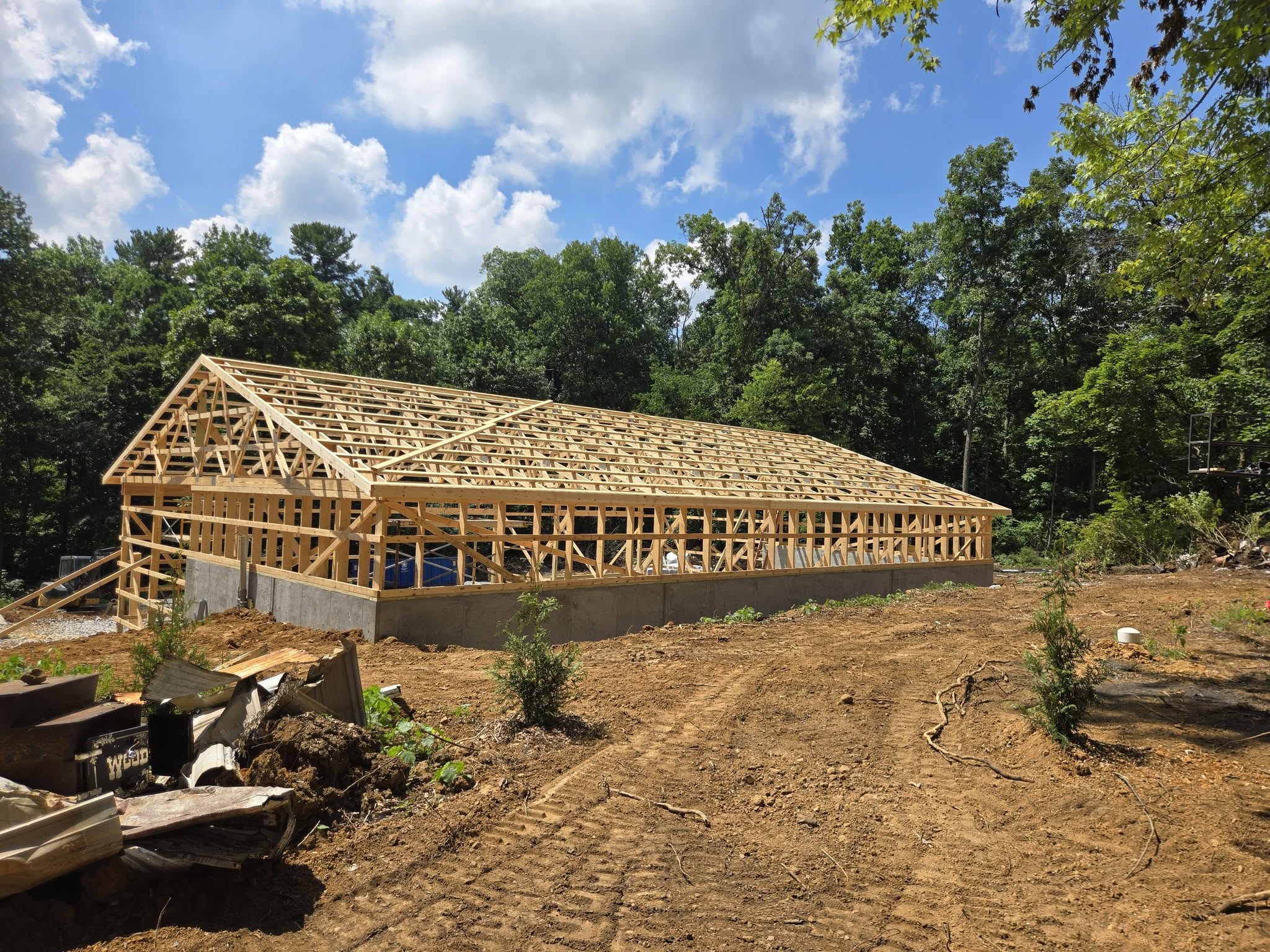 Large post-frame building with timber roof trusses set by the Harcon Services crew under a blue sky