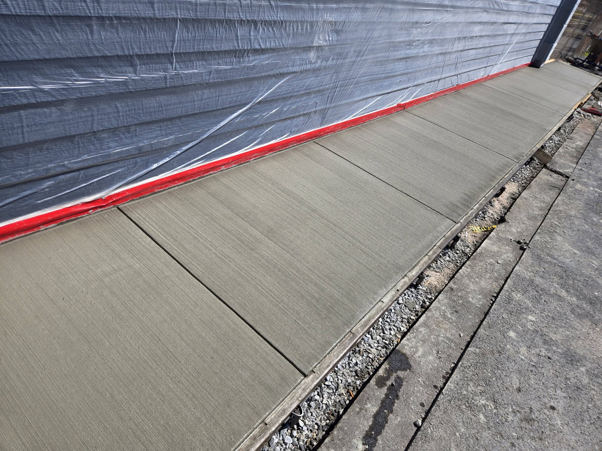 Freshly poured and finished concrete slab with clean edge and stone base