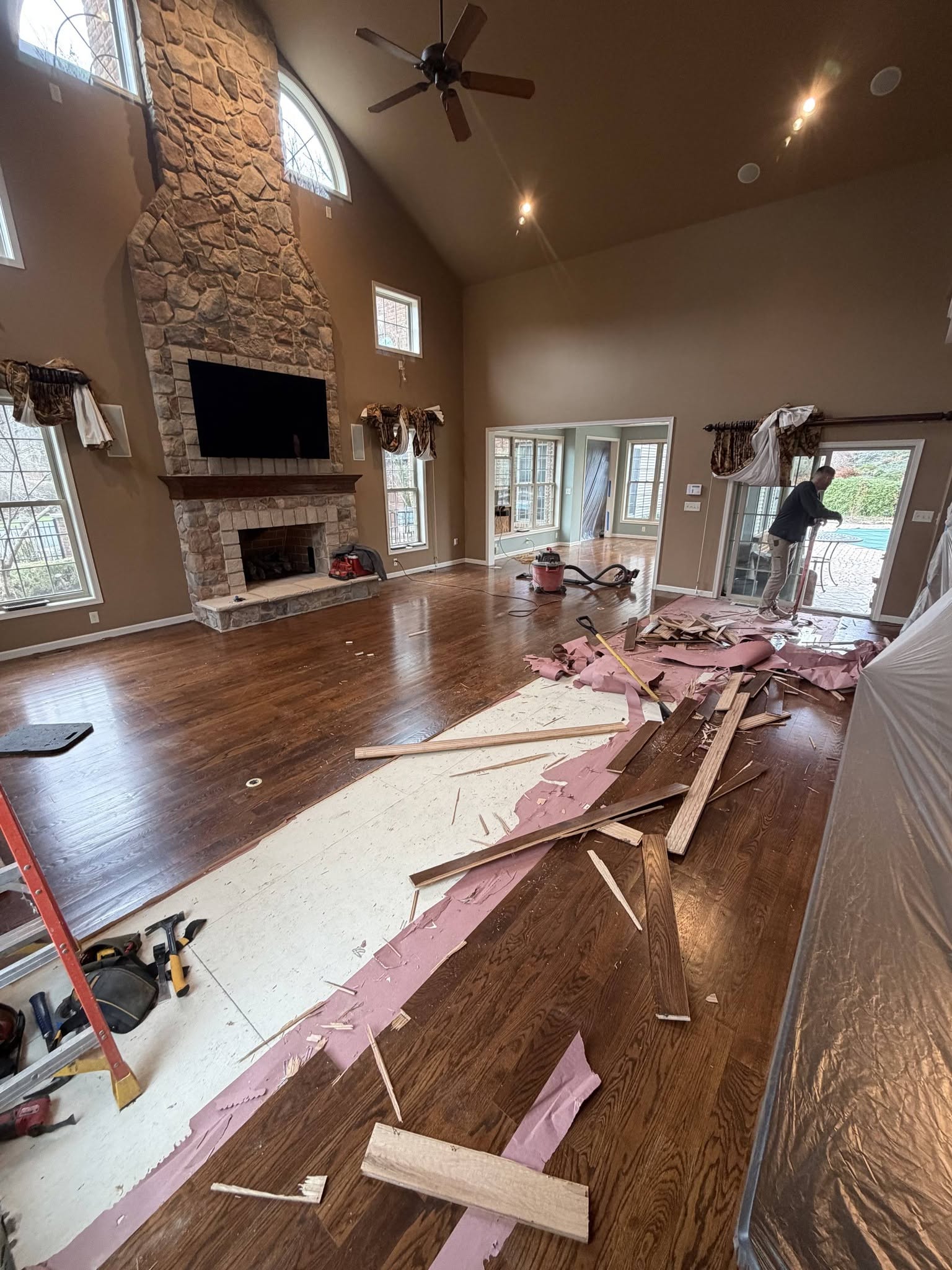 Interior remodel in progress with new hardwood flooring and a stone fireplace
