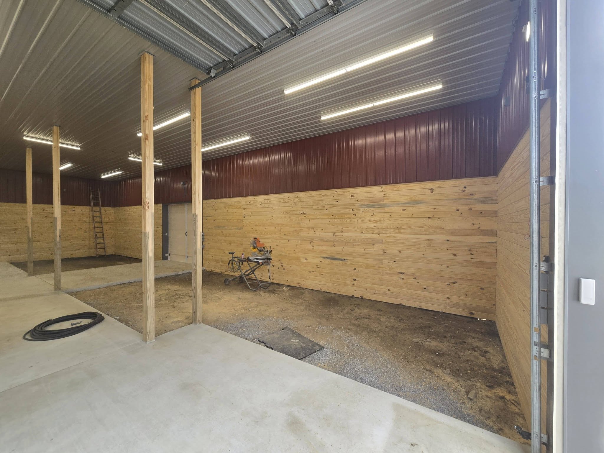 Finished barn interior with burgundy steel liner panels, pine wainscot and LED strip lighting