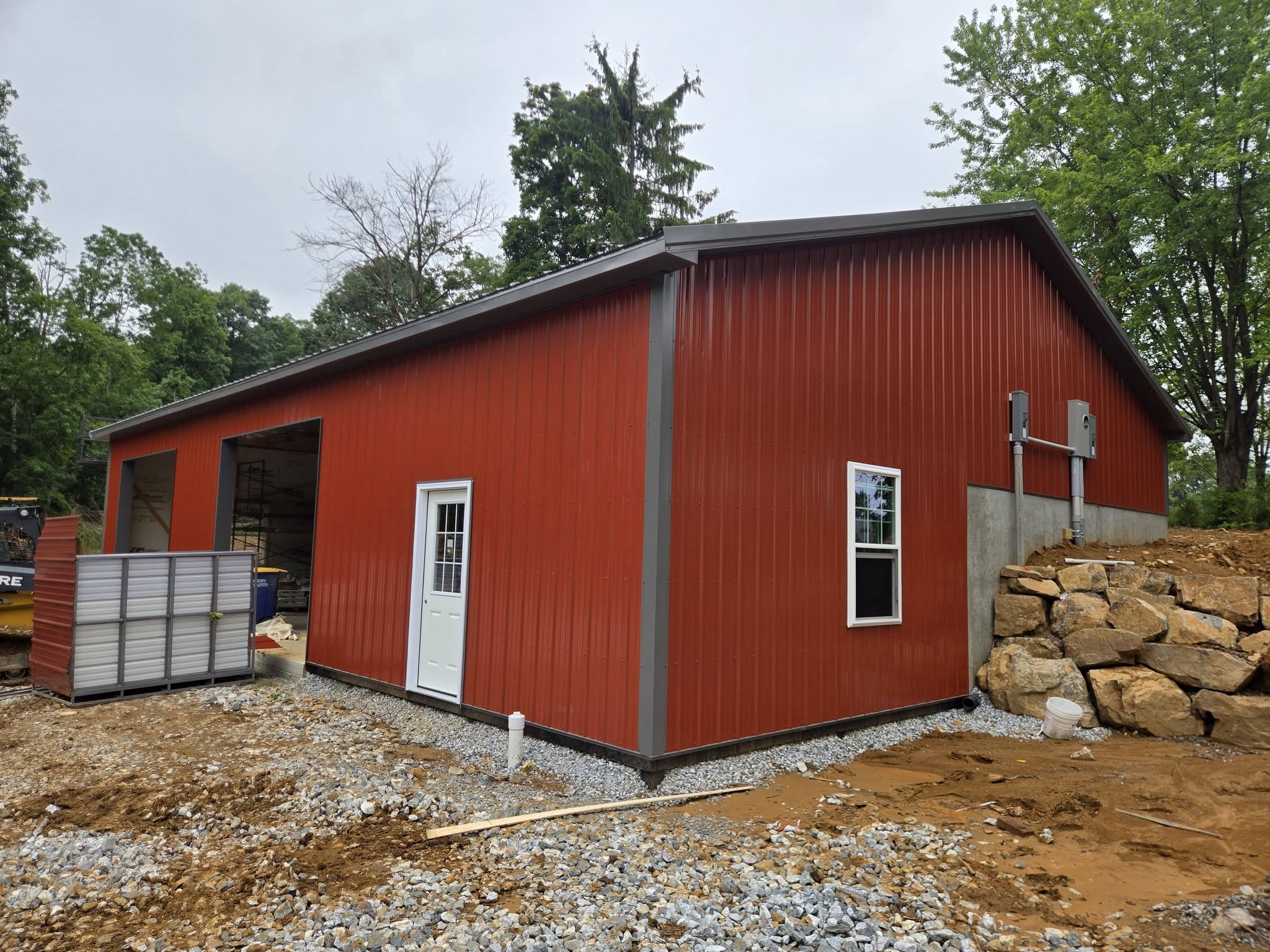 Finished red post-frame pole barn with white trim, service door and windows