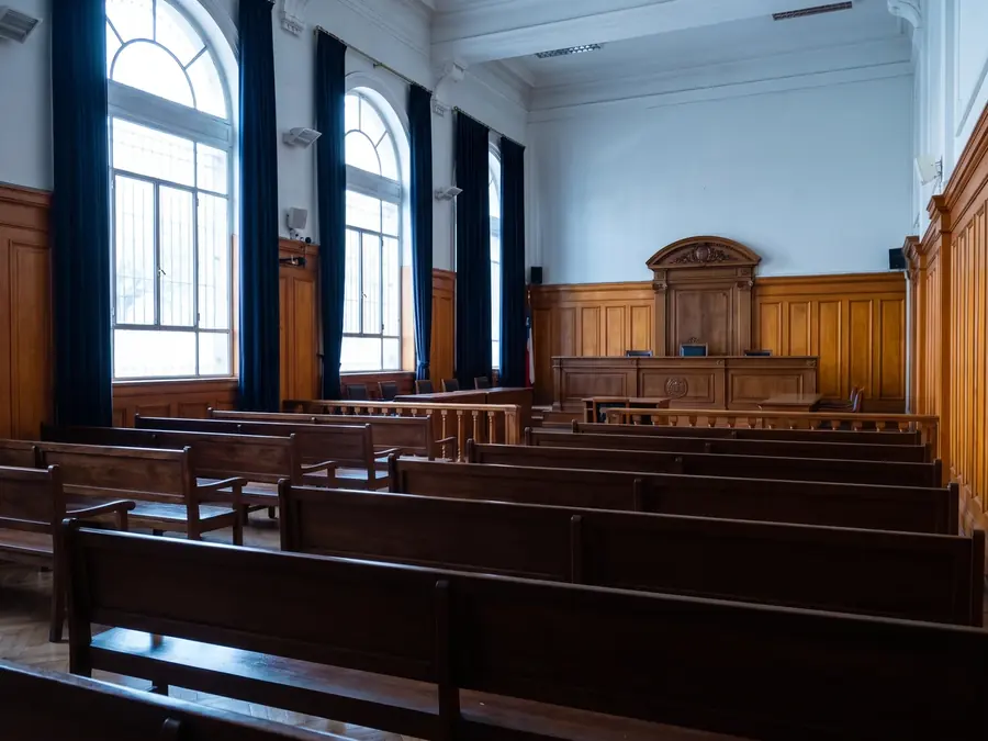 Sala de audiencias de un tribunal chileno vacía, vista desde el fondo, luz fría