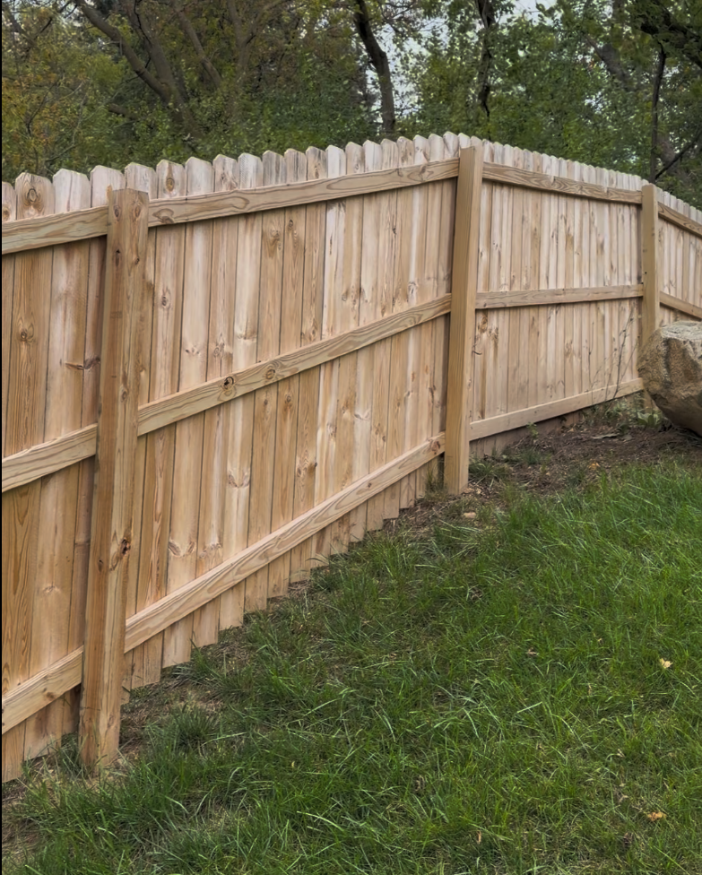 Six-foot pressure-treated pine privacy fence with dog-ear pickets in a Wisconsin backyard