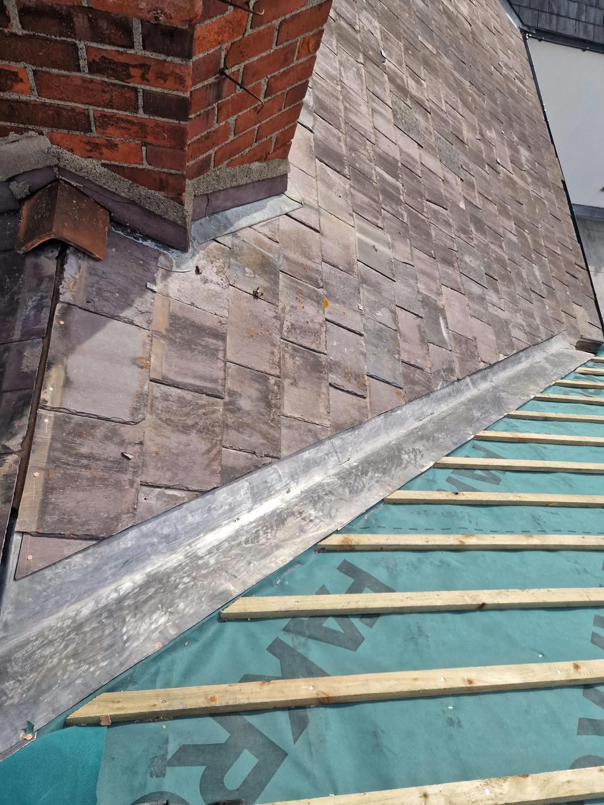 Lead valley meeting a slate roof below a brick chimney with lead flashing in Portobello, Dublin 8