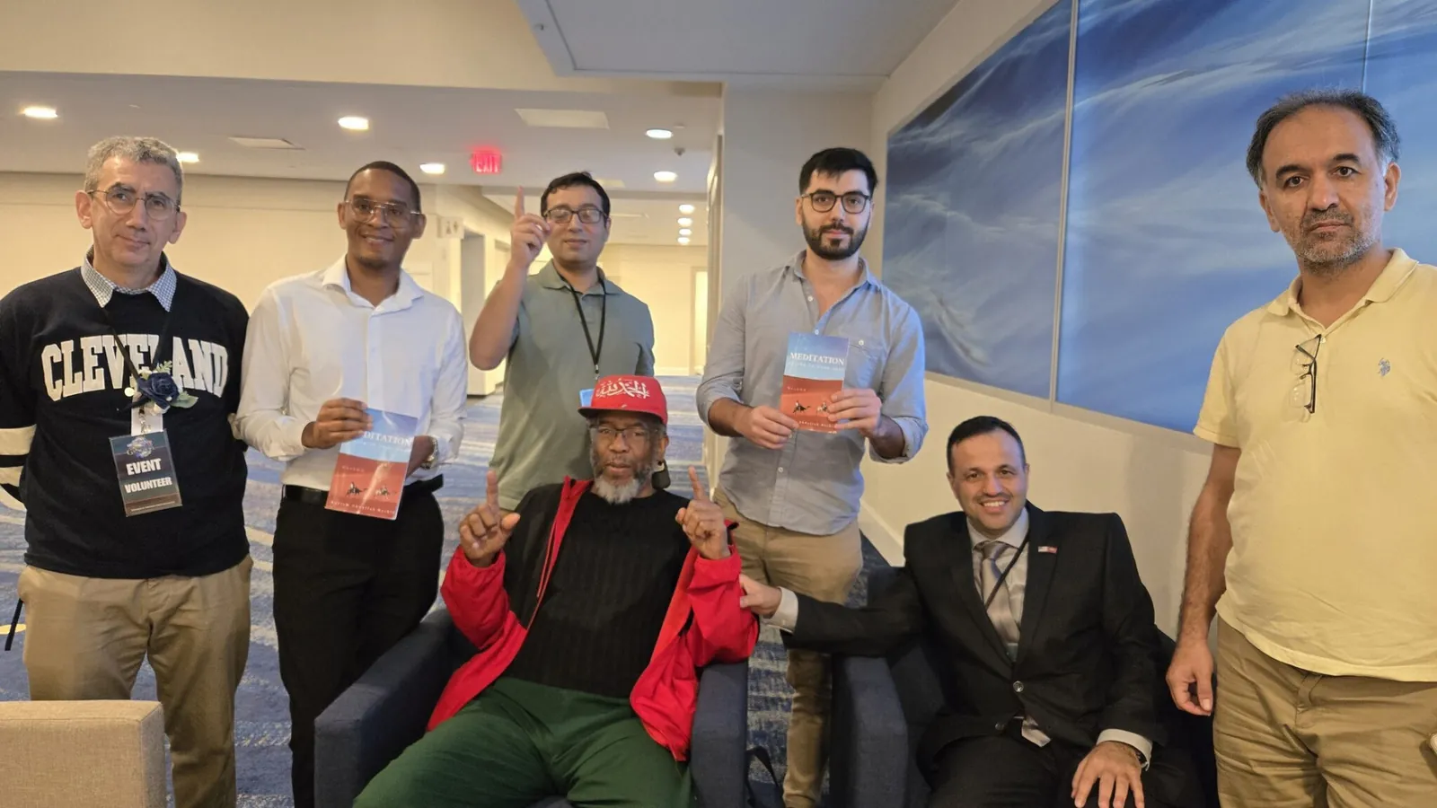 Kariem seated with a group of friends, two of them holding his book