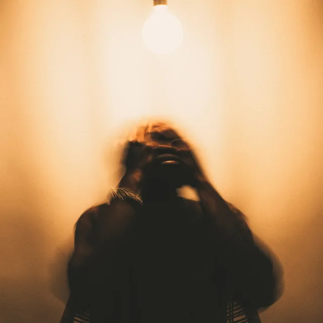 MAN PLANz, GOD LAUGHz cover: a bare bulb in an amber room