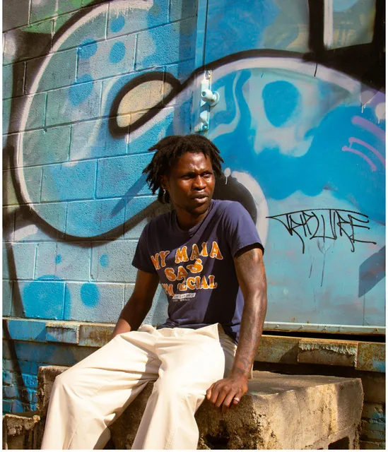 Will Kobus sitting on a concrete ledge in front of a graffiti wall