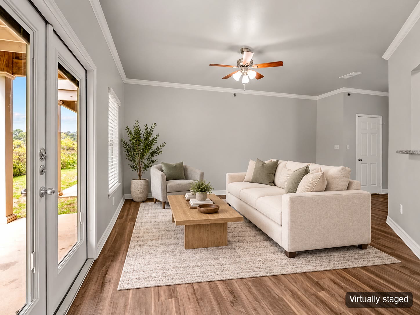 Living room with sofa and French doors to the patio (virtually staged)