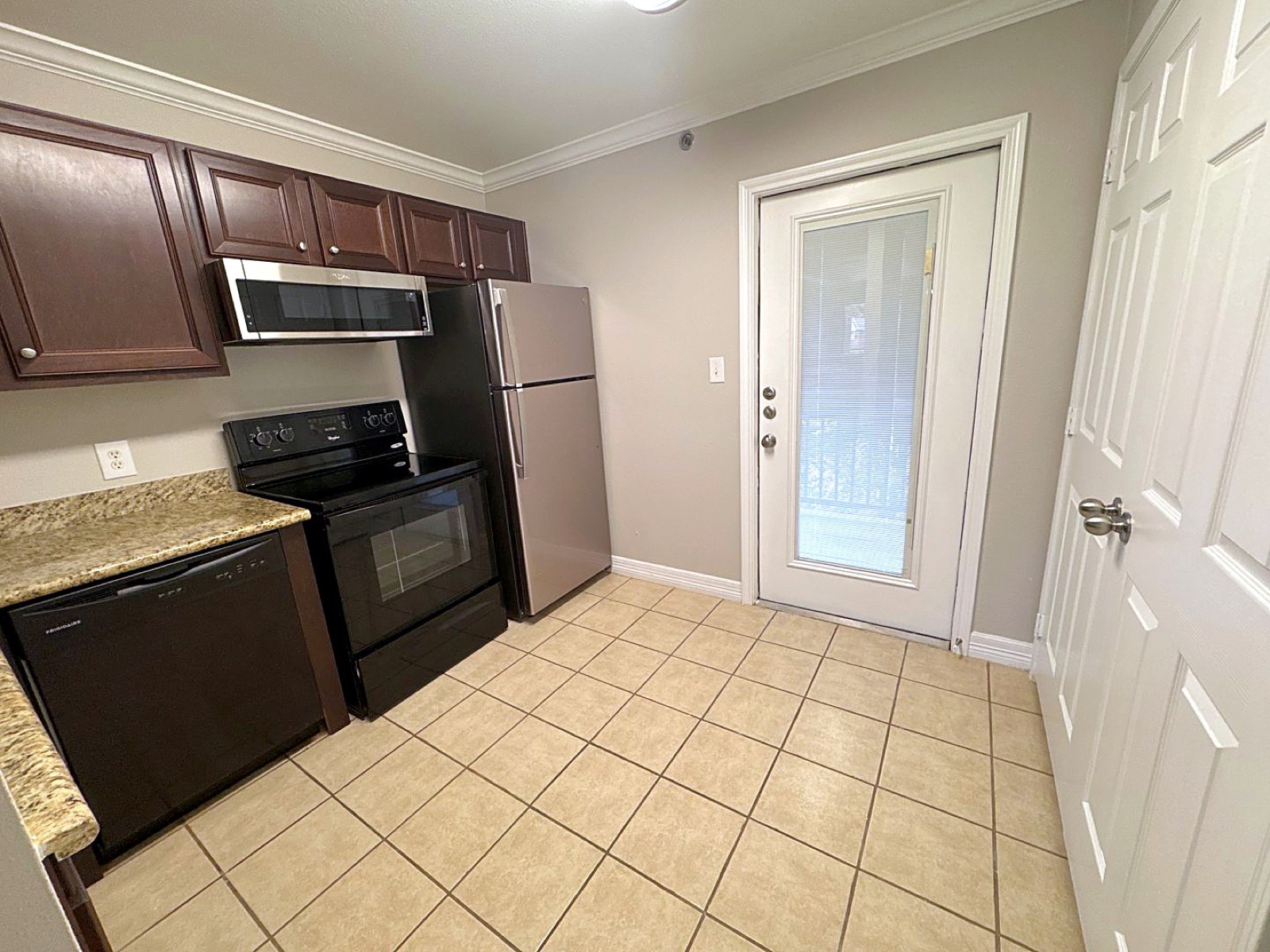 Apartment kitchen with dark wood cabinets and a patio door at Grace Pointe, Longview, TX