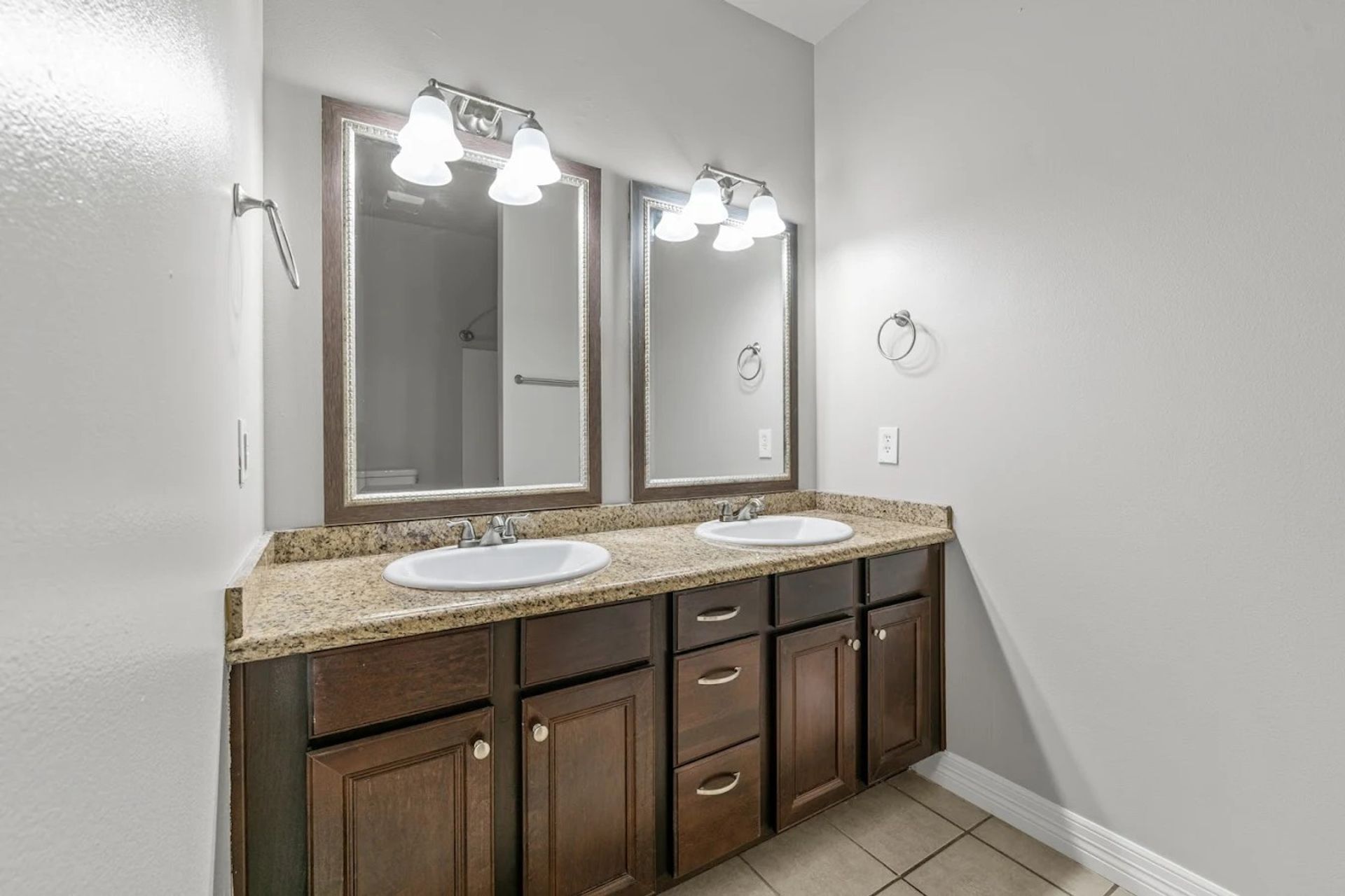 Bathroom with a double vanity, granite counter and framed mirrors