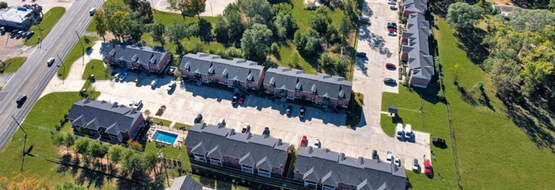 Aerial view of the community showing buildings, parking and the pool