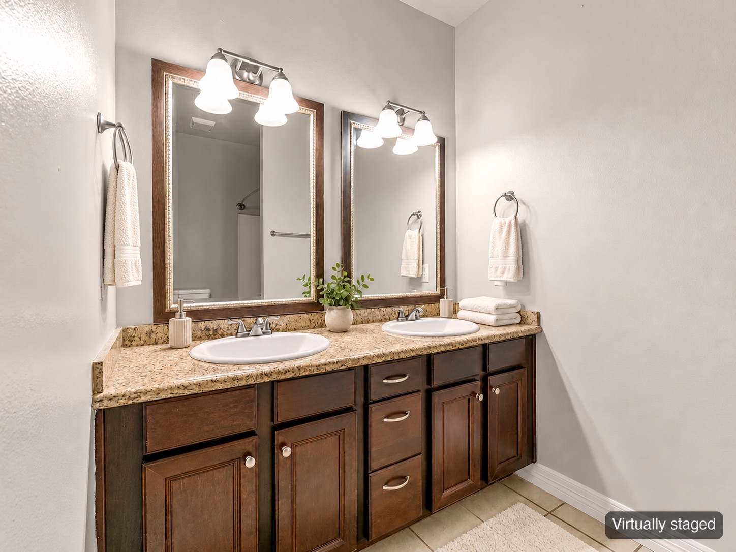 Bathroom with double vanity, framed mirrors and hand towels (virtually staged)
