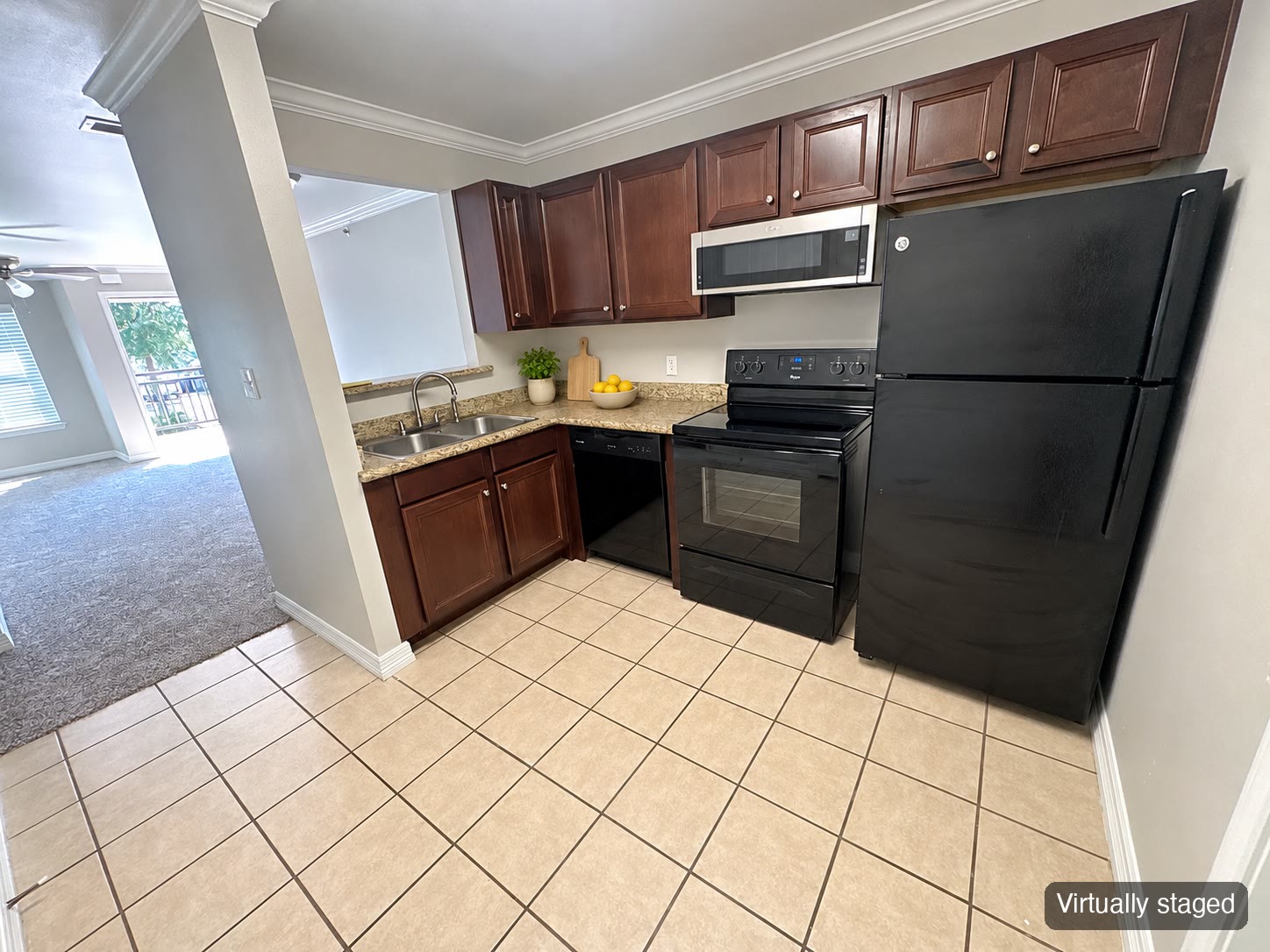 Kitchen with dark wood cabinets and black appliances (virtually staged)
