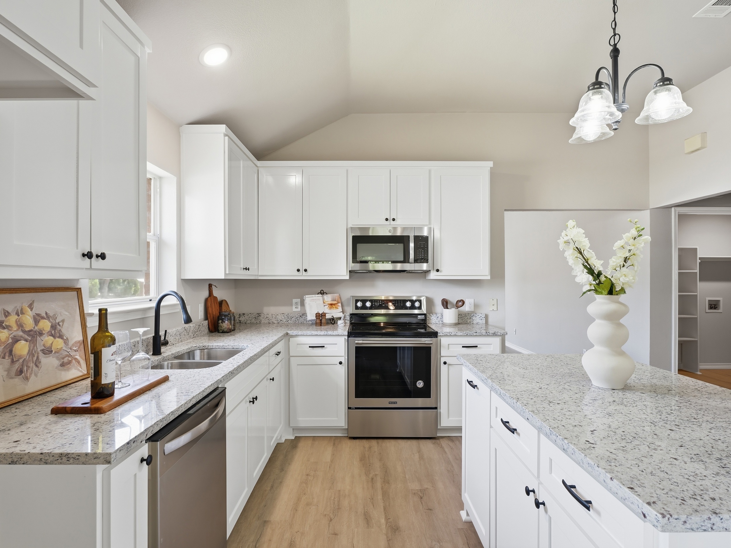 Same kitchen photographed with bracketed HDR — white cabinets rendering correctly against a balanced window