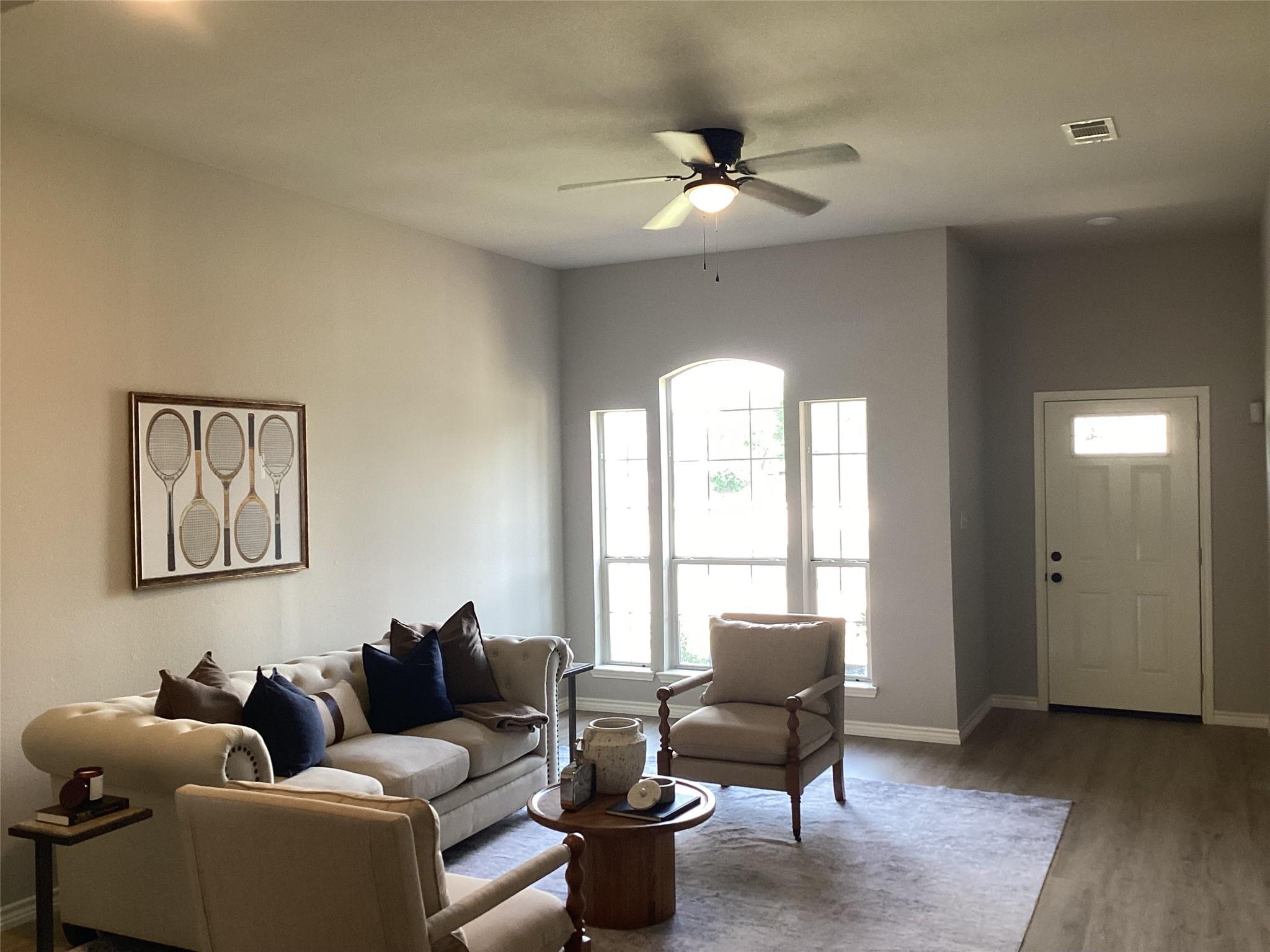 Living room in the previous listing photos — grey-blue colour cast with the ceiling fan running and the window blown out