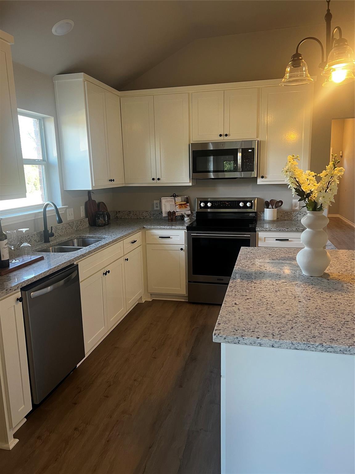 Kitchen in the previous listing photos — lit by one warm overhead with the window blown out behind it