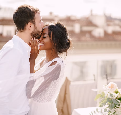 interracial couple kissing at outdoor wedding