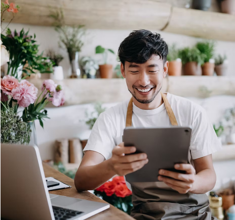 happy asian male florist working on tablet
