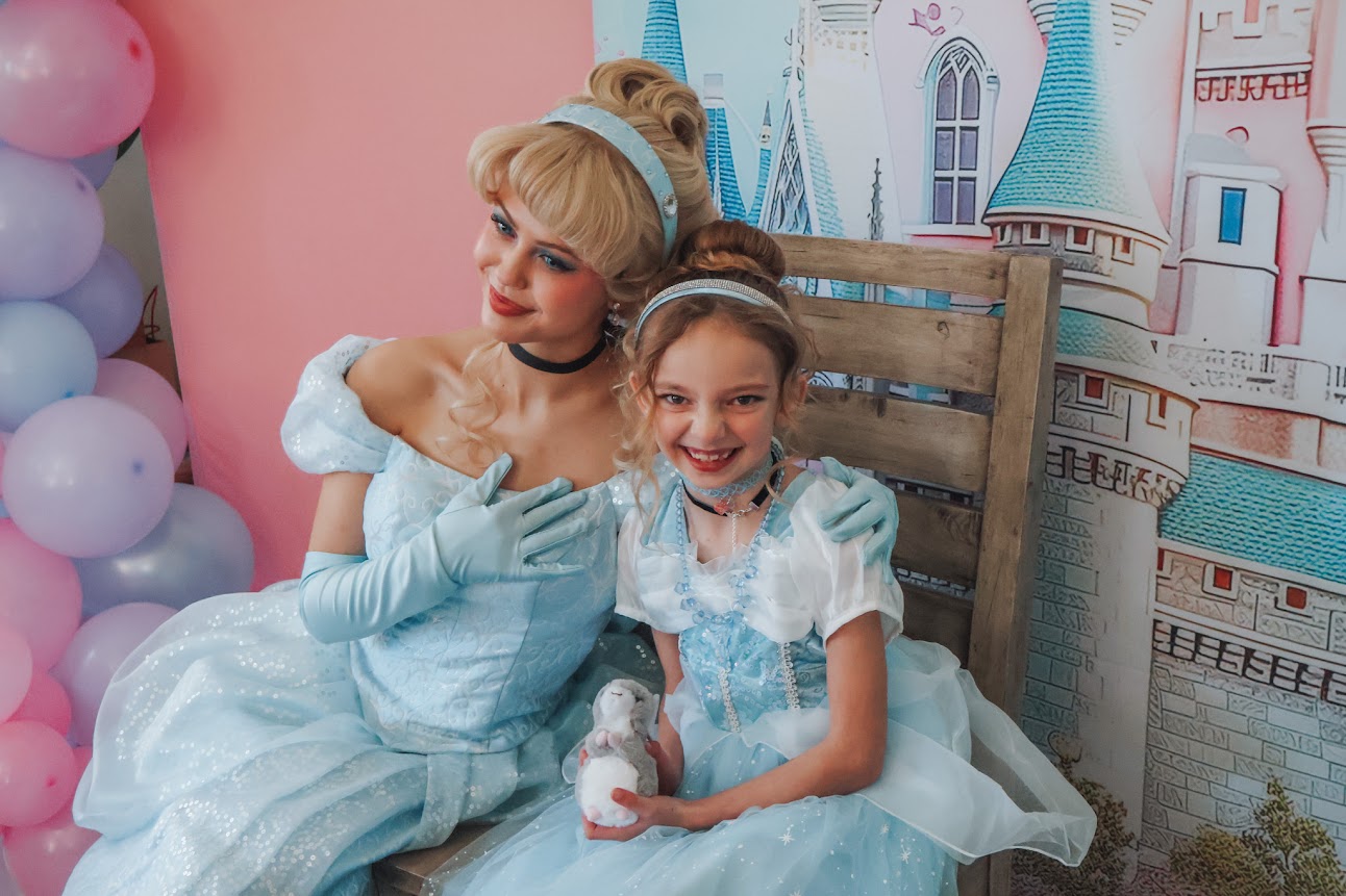 A princess performer sharing a celebration with a young guest in a blue dress