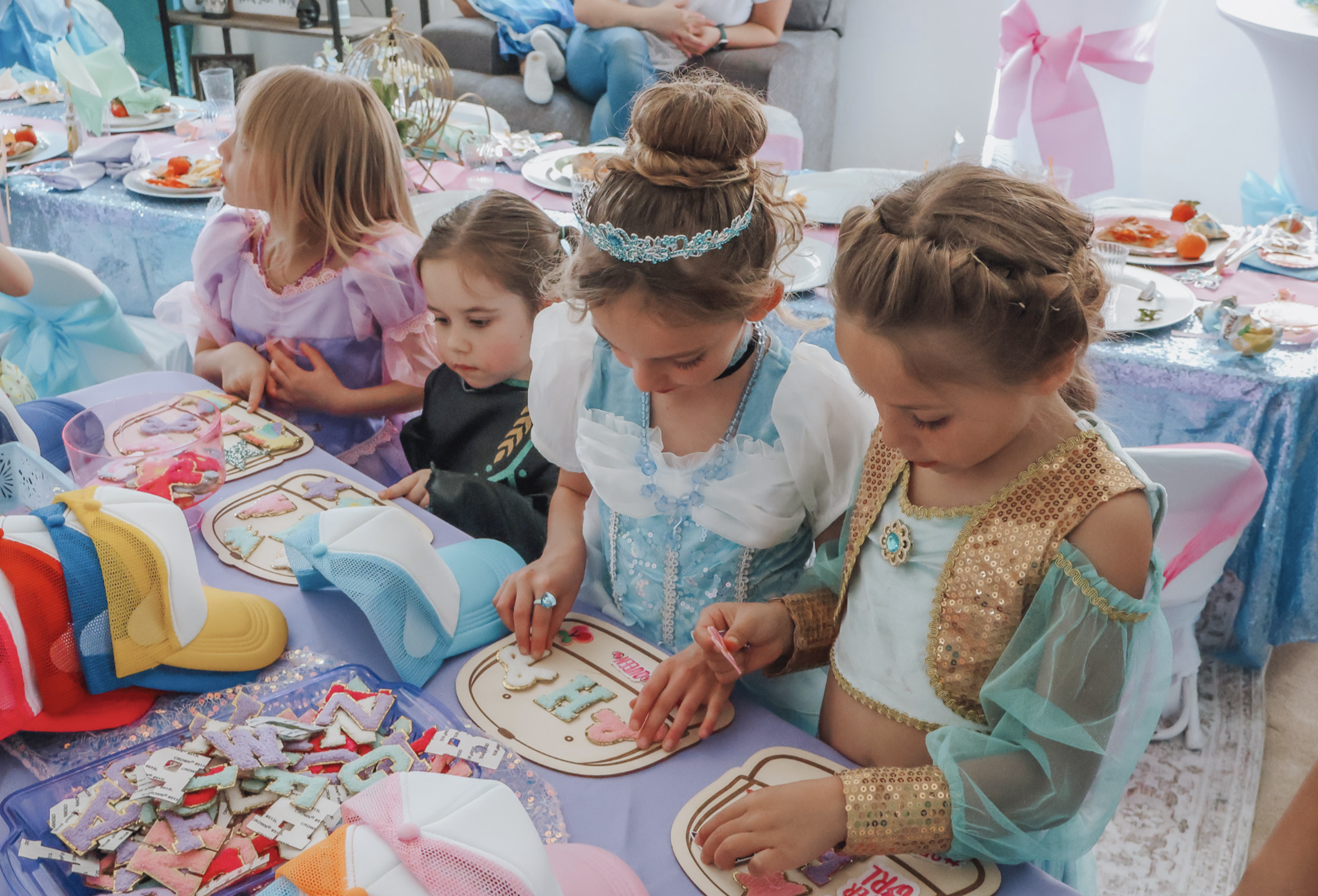 Young guests in princess costumes gathered around decorated tables at a Cinderella-themed birthday party