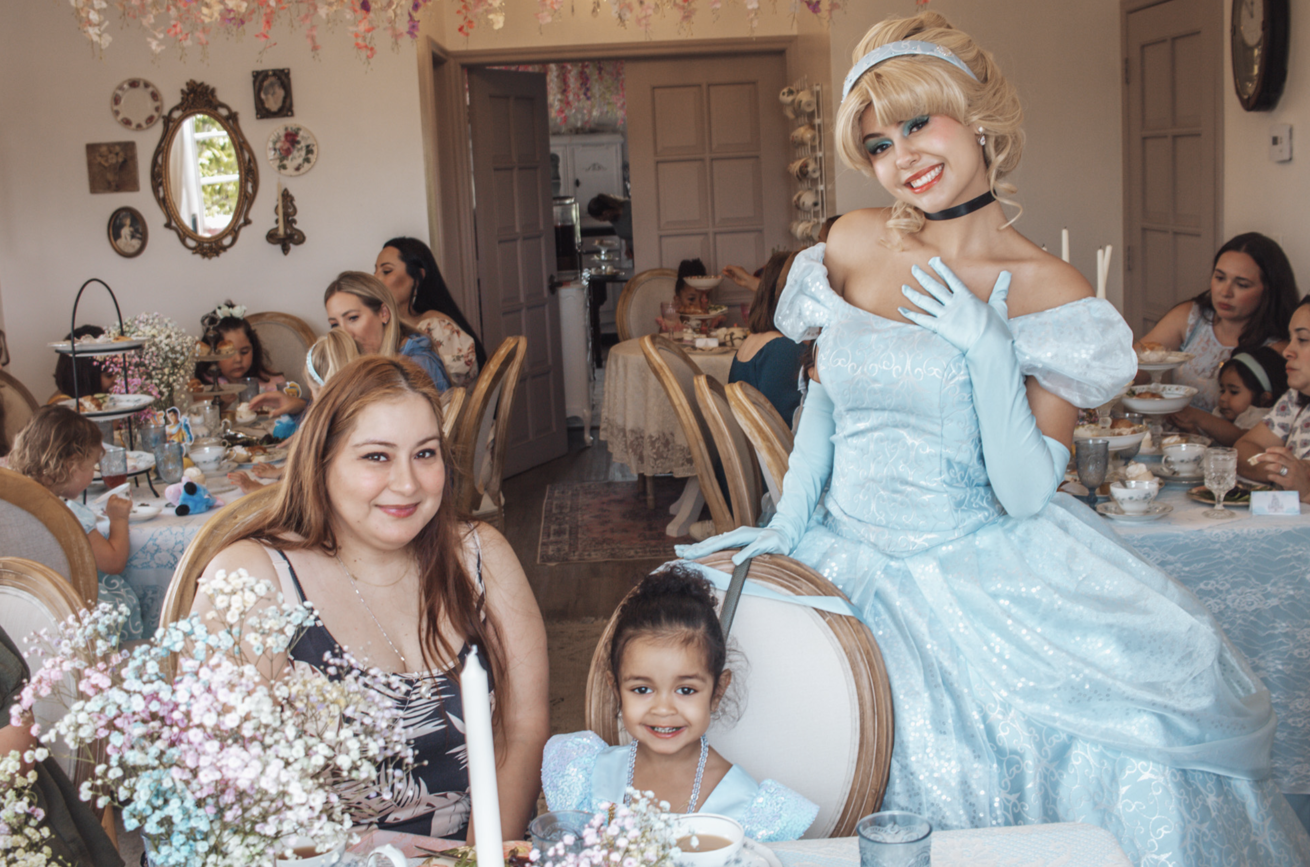 Cinderella greeting guests in a tea-party setting with decorated dining tables