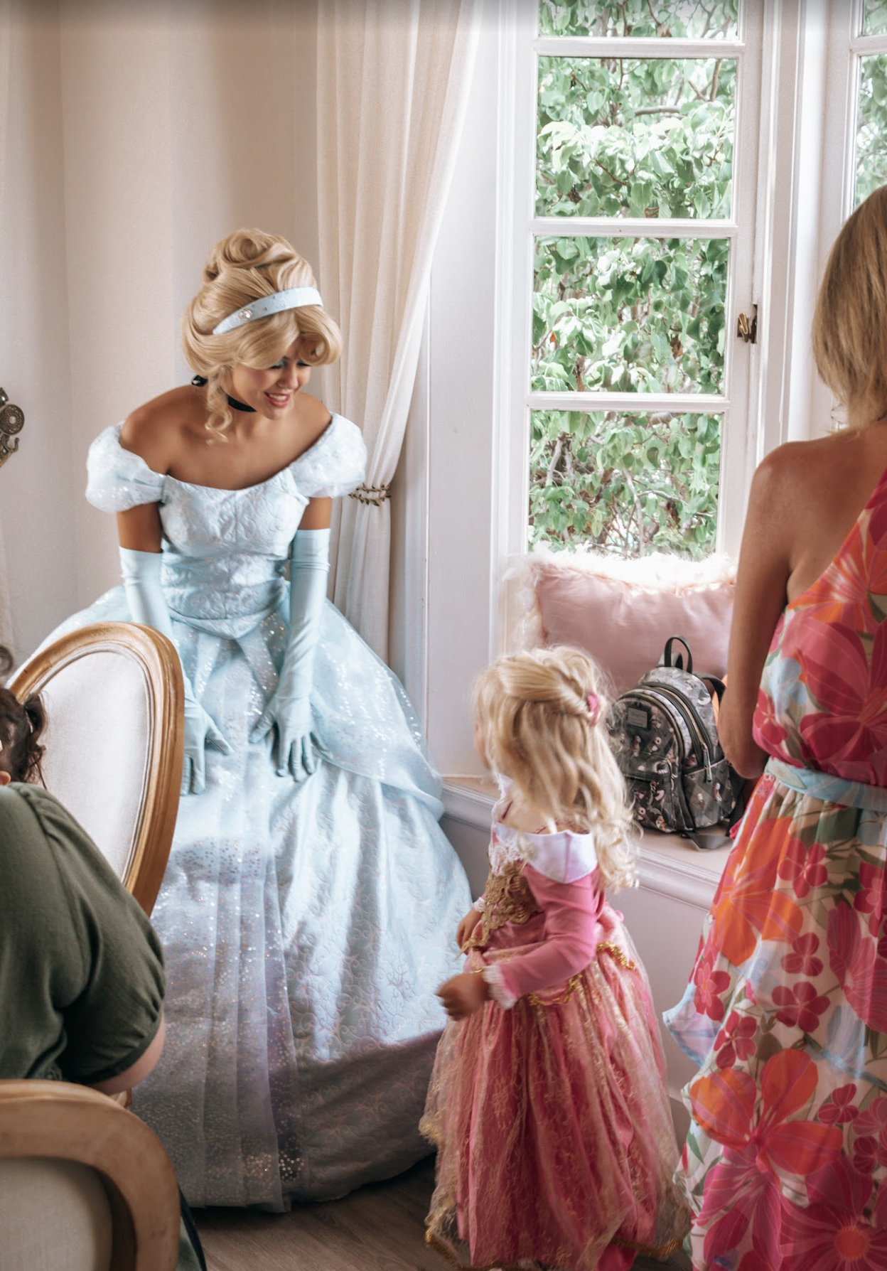 Cinderella sharing a greeting with a young guest in a tea-party room