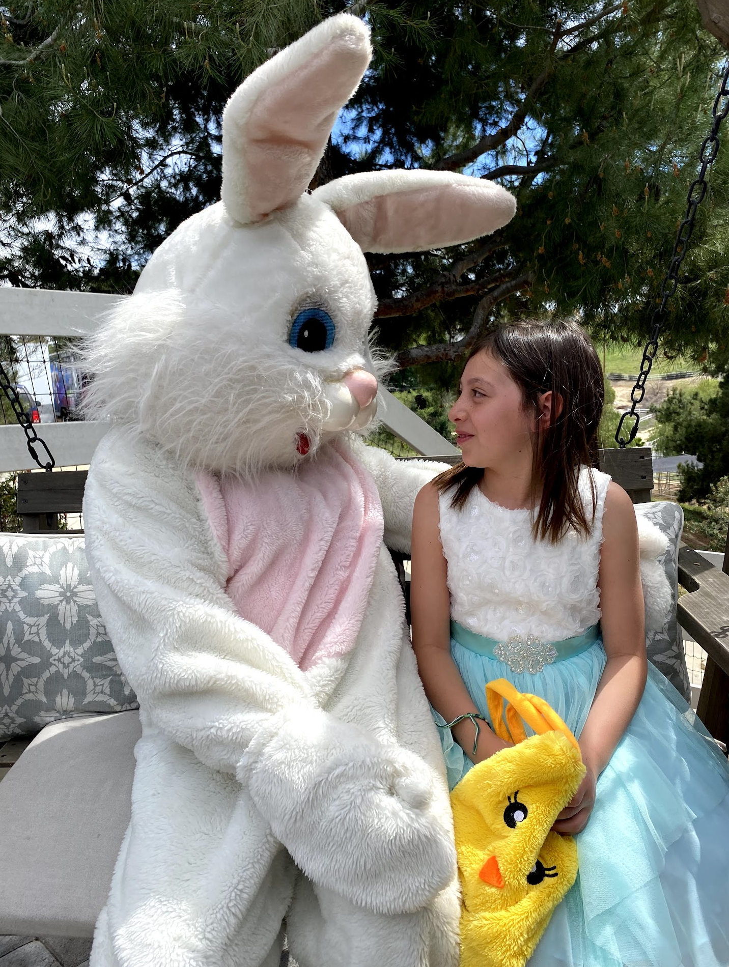 The Easter Bunny sharing a greeting with a young guest on an outdoor garden swing
