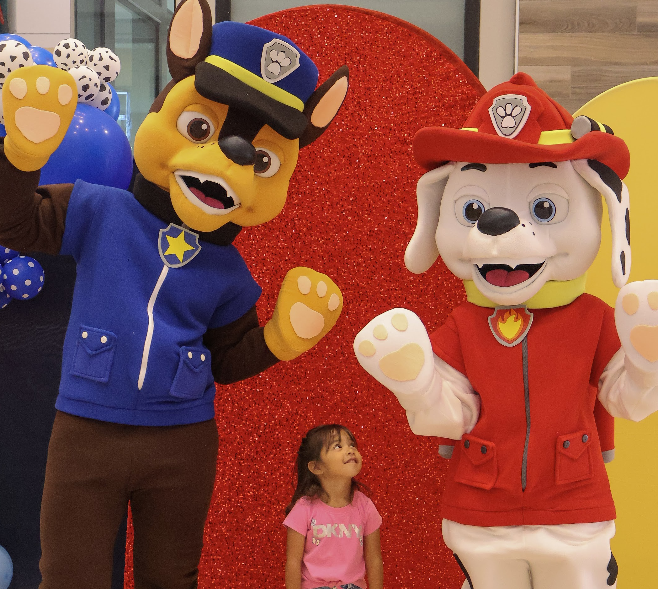 A young guest looking up at two friendly dog mascots in a colorful photo setting