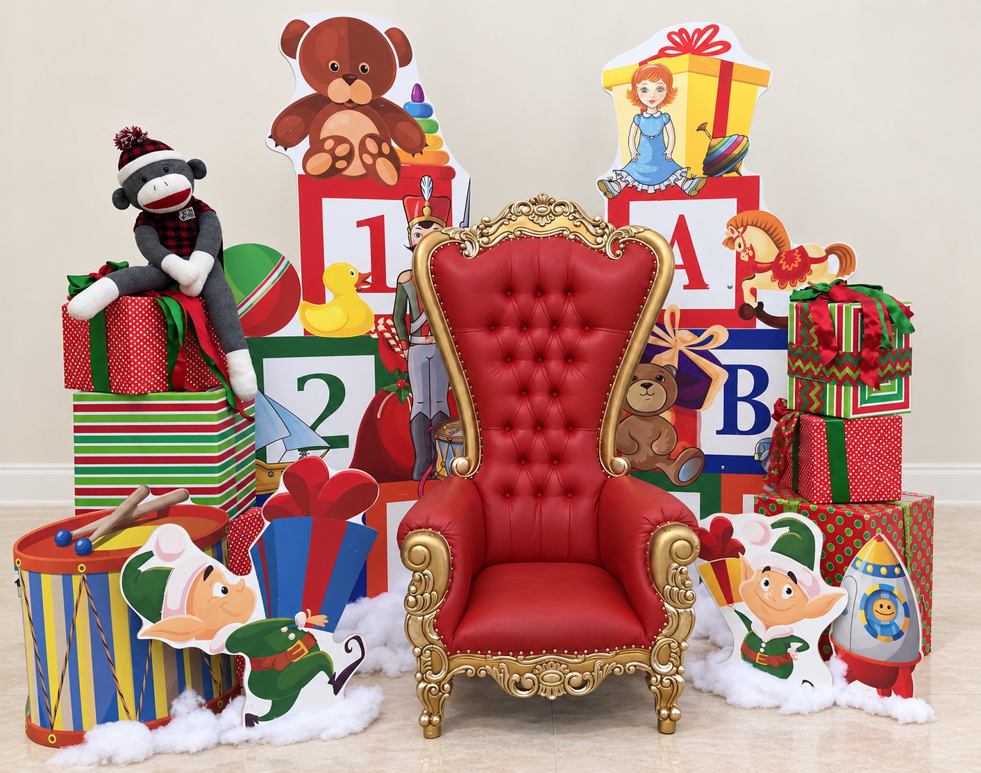 Holiday photo backdrop set with a red and gold throne, oversized toy blocks, wrapped gifts and festive props