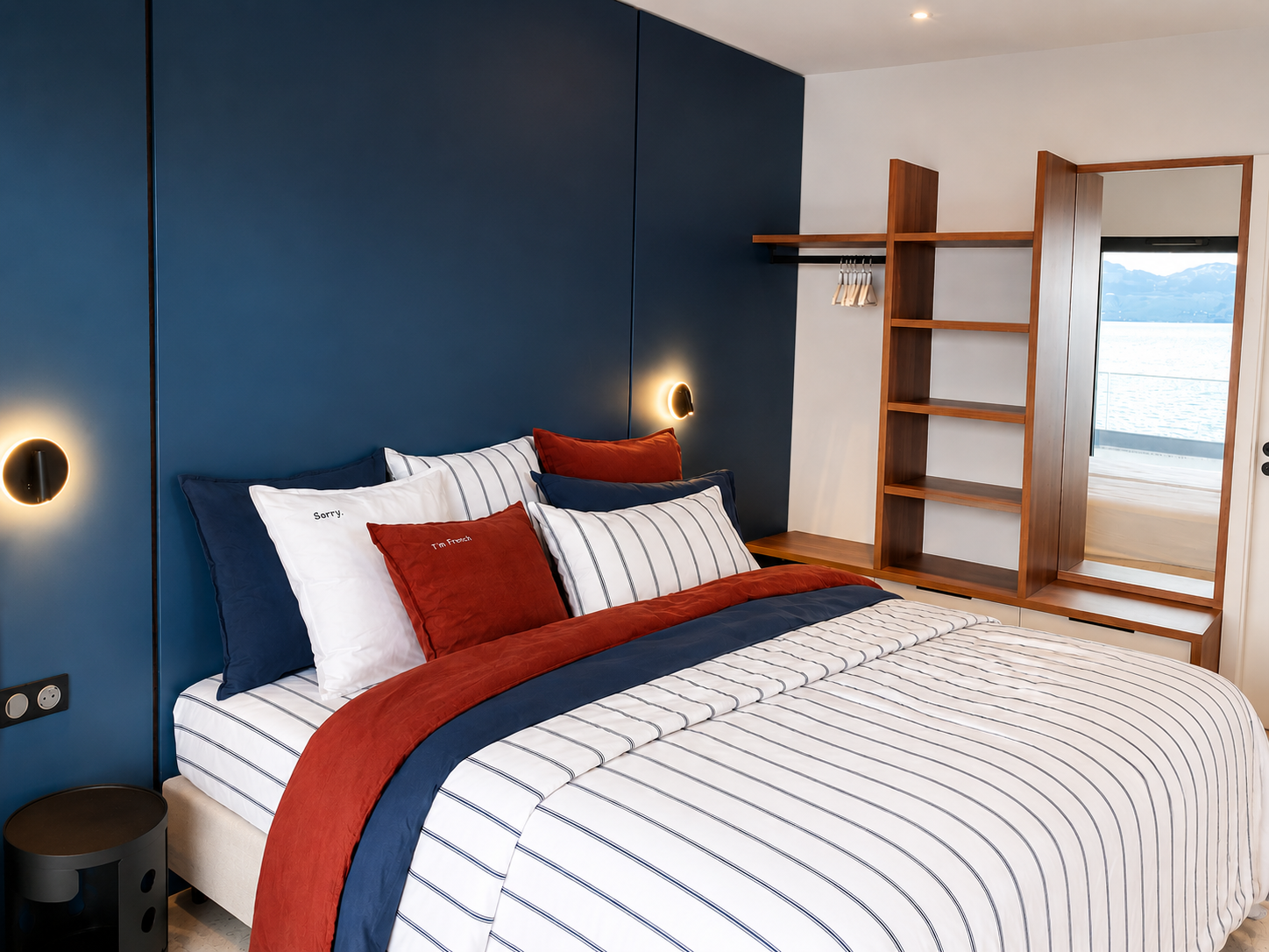 Chambre 1 : mur bleu baltique, tête de lit et étagères noyer, vue lac
