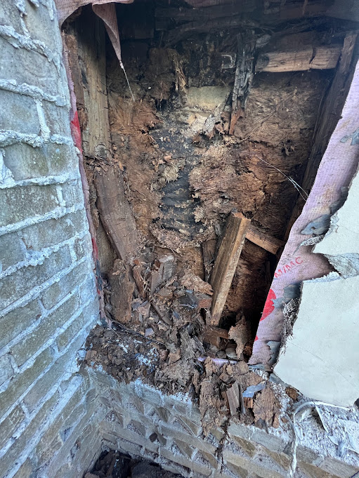 Opened wall behind painted brick revealing rotted framing where water got past the flashing