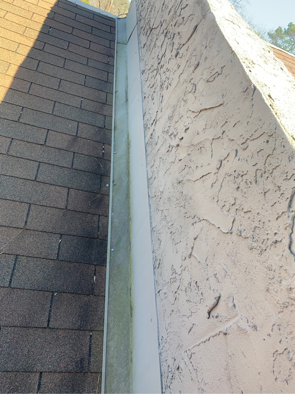 Stucco wall running down to a shingle roof with no counter flashing at the junction
