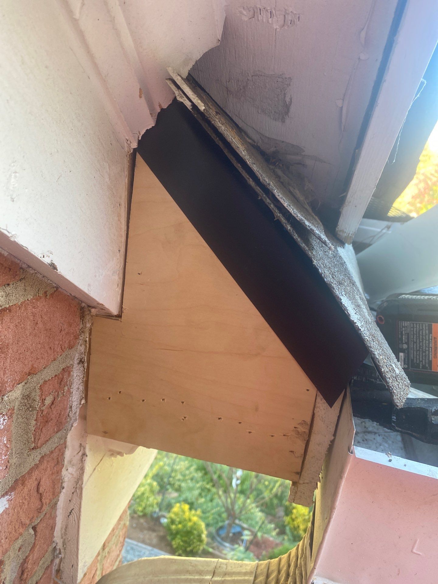 Dark fascia board pulling away from a brick wall with the roof edge exposed above it