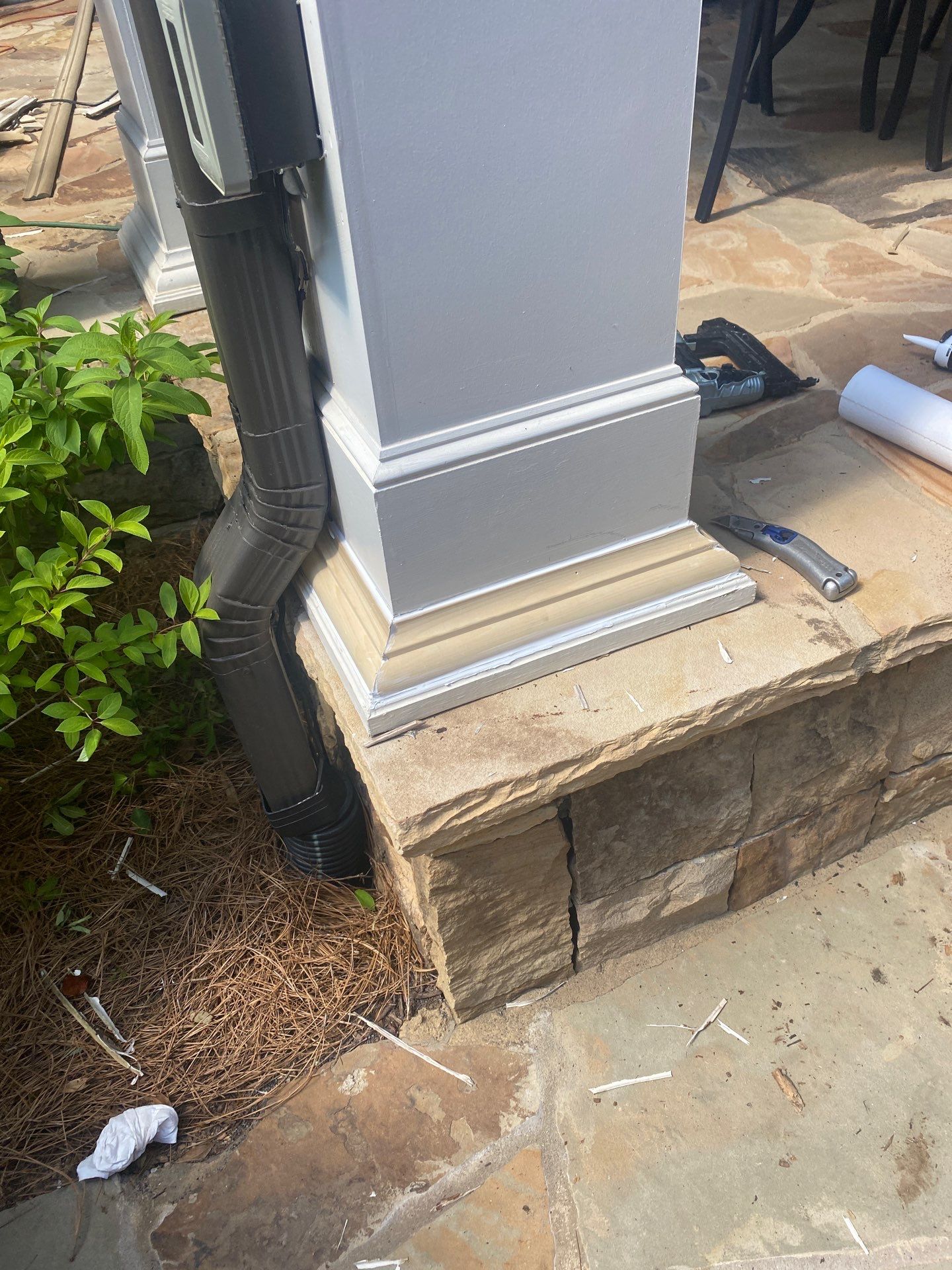 New white trim being fitted around a column base over a stone landing during a repair