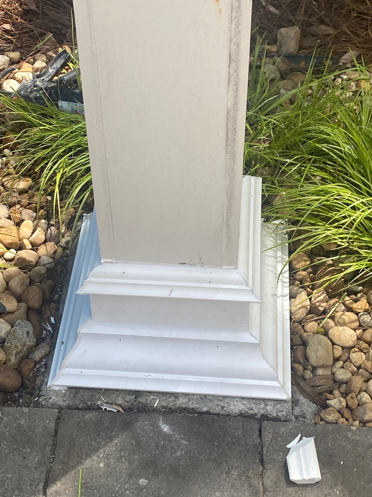 Finished white column base trim sealed and painted against landscape rock and plantings
