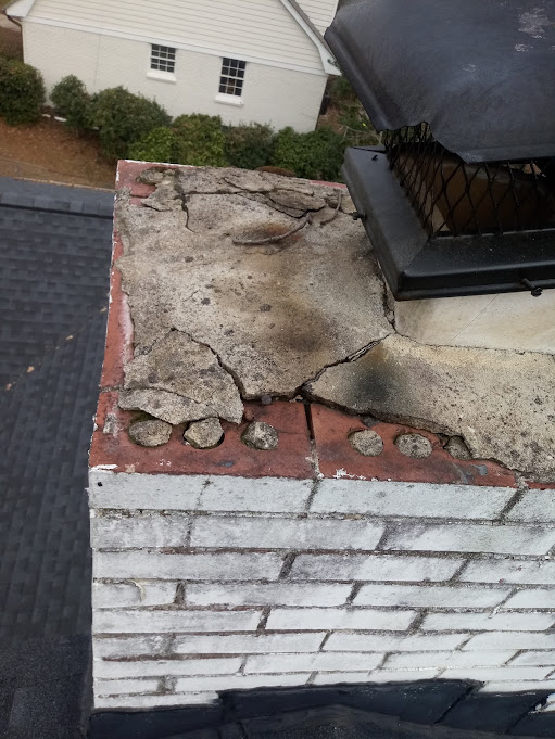Mortar crown cracked and lifting away from the brick beside a black chimney cap