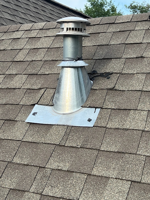 B-vent flashing with a metal storm collar around a furnace vent pipe on an asphalt shingle roof