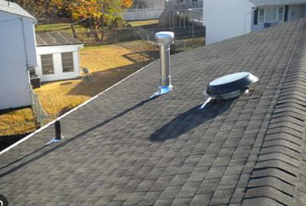 Shingle roof with a newly flashed B-vent pipe and a turbine vent, neighboring homes beyond