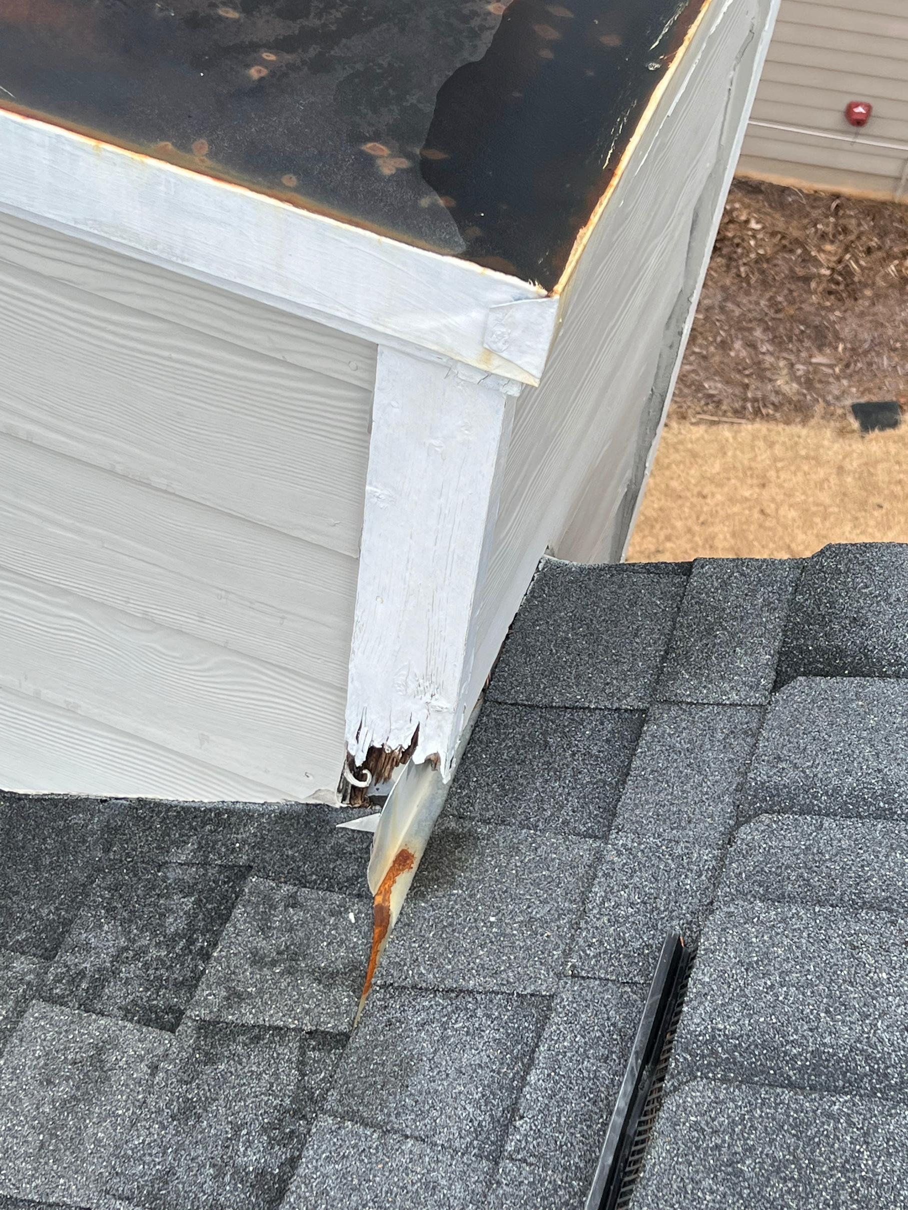 White fascia and trim board above a shingle roof with a gap where an animal has gotten in behind it