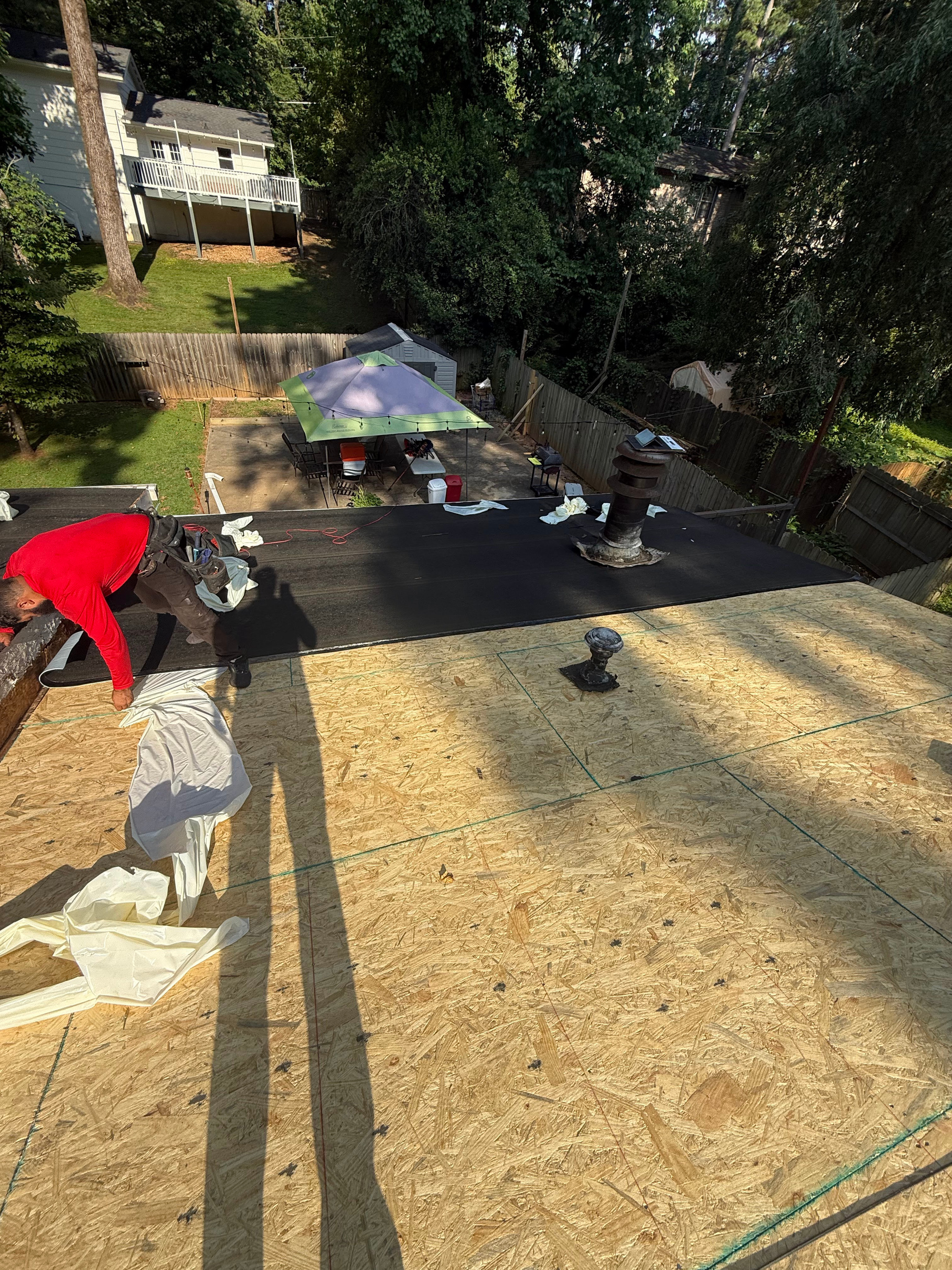Crew laying new underlayment over fresh roof decking on a sunny day