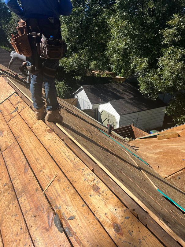 Roofer standing on exposed roof decking with new boards laid along the slope