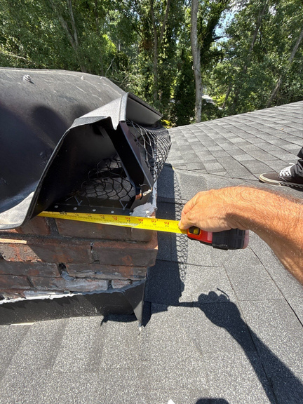 Shelter Guard technician measuring a chimney chase opening with a tape measure