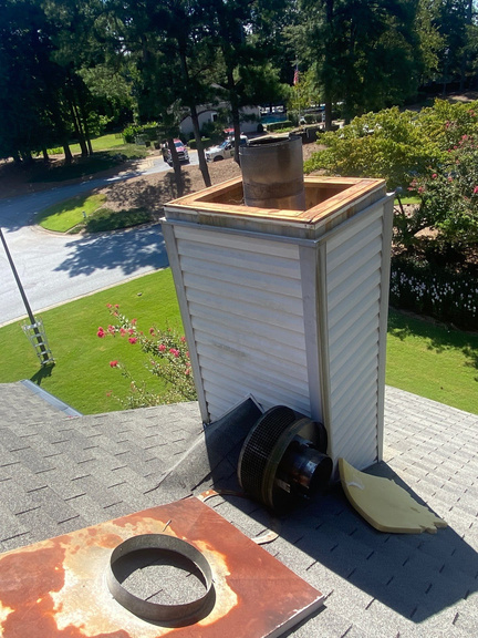 Newly installed metal chimney chase cap with vent stack on a Marietta home